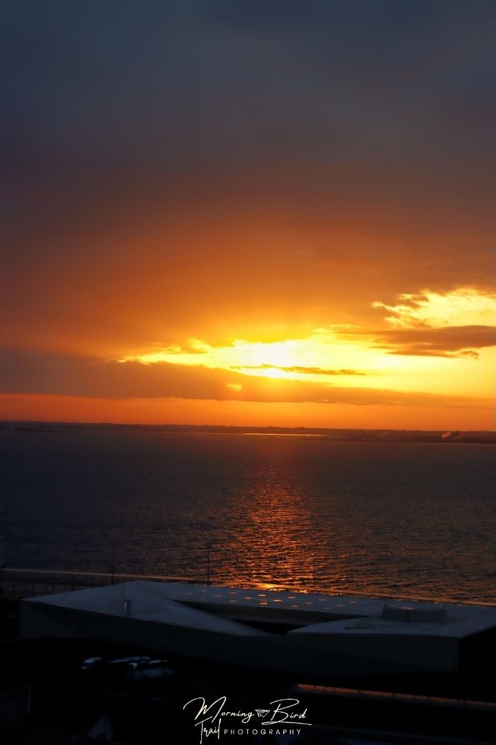 Photo with the sunlight hiting the river Tagus and the top of the new Lisbon port at sunrise