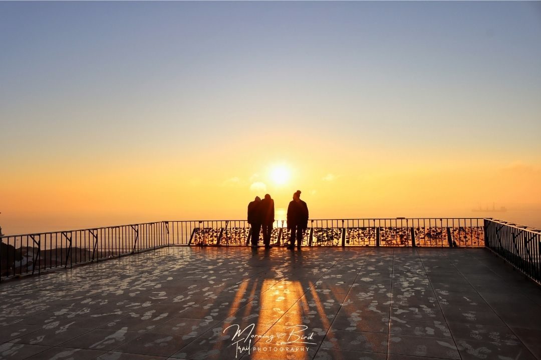 People looking at a beautiful sunrise in Portas do Sol viewpoint, Lisbon