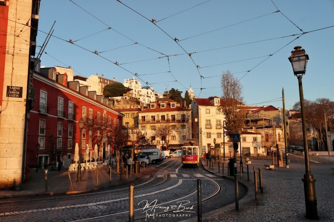 Beautiful light hitting the buildings in Largo de Santa Luzia in Lisbon at sunrise. In this moment there is also a 28 Tram passing by to complete the picture.