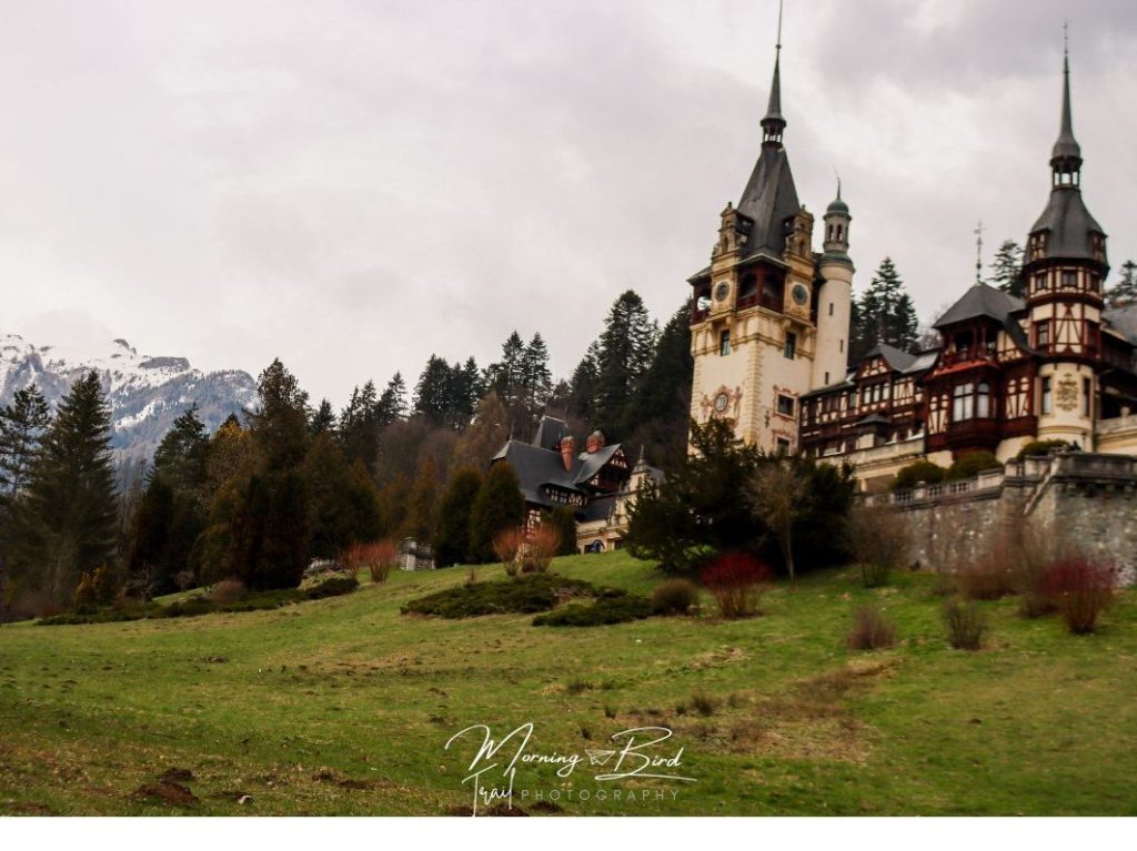 Peles Castle in romania with snowy mountains on the back.